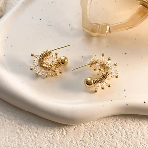 Detailed macro shot of gold-plated U-shaped earrings with hand-wrapped crystals and beads