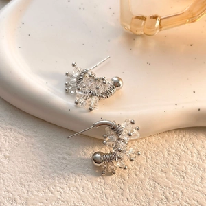 Macro detail of silver U-shaped earrings showing fine wire wrapping and 925 silver stamp