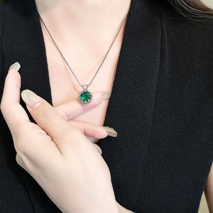 Detail of elegant silver box chain necklace with large emerald green zircon pendant on model