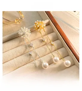 Detail of long pearl tassel earrings in gold and silver finish with sparkling zircons