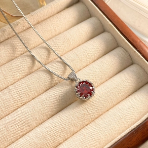 Detail of zircon bud pendant necklace with box chain in a velvet jewelry box