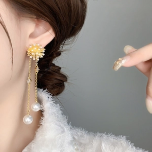 Detail shot of gold long tassel earrings featuring pearls and starburst motifs on ear