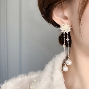 Close-up of long tassel pearl earrings with snowflake studs and zircon crystals