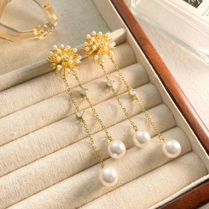 Close-up of gold tassel earrings with snowflakes, small pearls and sparkling zircons