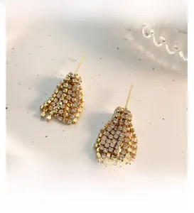 Detail von Luxus-Quastenohrringen aus Gold mit funkelnden Kristallen auf Keramik