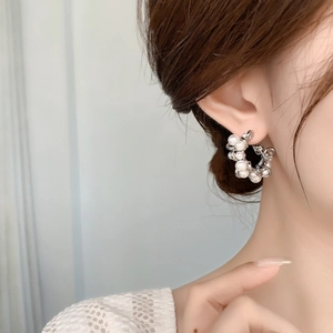 Detailed close-up of a silver twisted brass hoop earring with elegant white pearls