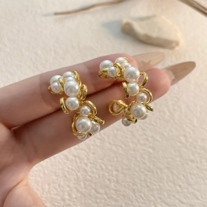 Macro detail of elegant gold-toned earrings featuring multiple white cluster pearls
