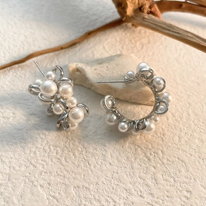 Close-up of elegant silver brass hoop earrings with clusters of white round pearls