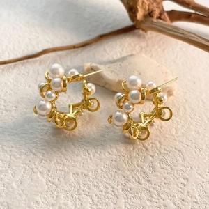 Detailed shot of brass earrings with white pearls on a textured stone surface