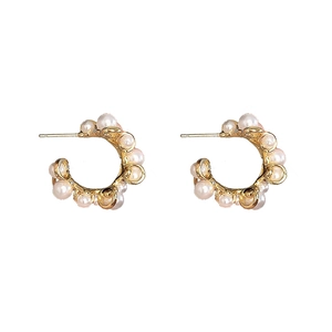 Detail view of C-shaped brass hoop earrings with elegant white pearls on gold finish