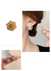 Close-up of sparkling zircon snowflake earrings in gold and silver finish for women