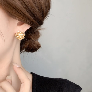 Close-up of a sparkling gold snowflake stud earring with white zircons on female ear