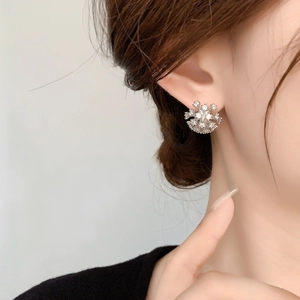 Close-up of sparkling snowflake stud earring with tiny zircons worn on model's ear