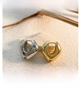 Détail des boucles d'oreilles cœur géométriques épaisses en finitions or et argent