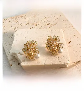 Detailed view of floral zircon earrings with gold finish and white pearls on stone