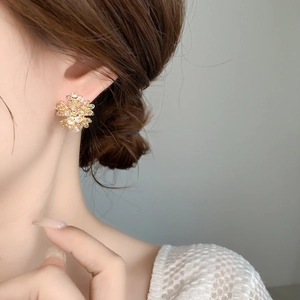 Close-up of a sparkling gold snowflake earring with micro-pave crystals on model's ear