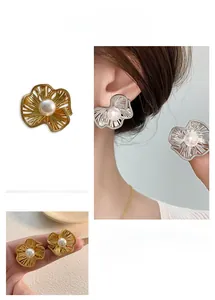 Detail of matte floral earrings with pearls in gold and silver finish on soft background