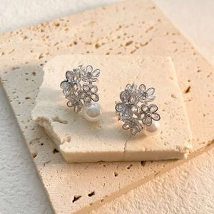 Macro shot of silver flower earrings with micro-set zircon and dangling pearls on stone