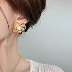 Detailed close-up of matte gold flower pearl earrings worn by a model in French style