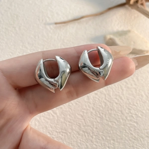 Gros plan de boucles d'oreilles cœur géométriques argentées au fini poli miroir