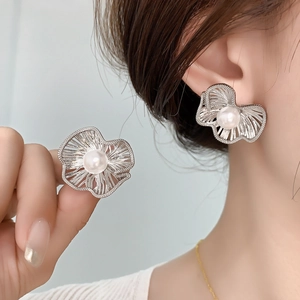 Matte silver flower stud earrings with central pearl on a model for elegant styling