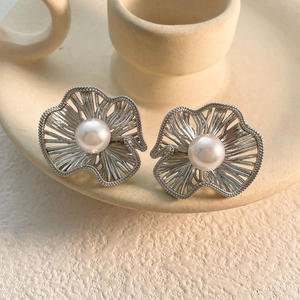 Macro view of silver floral stud earrings featuring hollow petals and center pearl detail