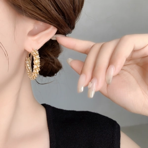 Close-up of golden wheat ear hoop earrings with zircon stones on female model's ear
