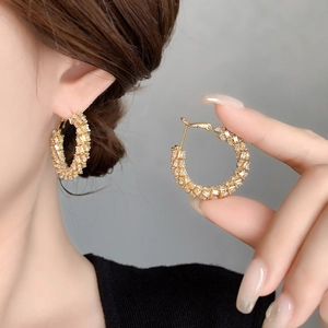 Golden wheat-pattern hoop earrings with zircon stones worn by a model in a high-fashion look
