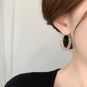 Close-up of silver hoop earring with pavé zircon wheat ear design worn on ear