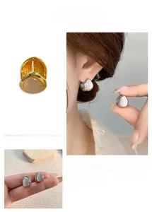 Macro detail of teardrop cat-eye stone earrings showing silver and gold plating