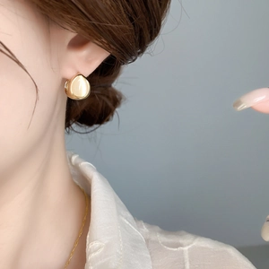 Close-up of elegant gold teardrop earrings featuring smooth yellow cat-eye stones on a model