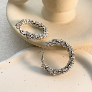 Macro shot of silver hoops with pave-set rectangular zircons on ceramic decor