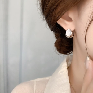 Close-up of a silver teardrop earring with cat eye stone on ear for an elegant look