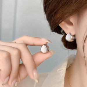 Silver teardrop earrings with white cat eye stones shown on model for a refined look