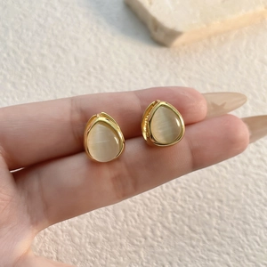 Golden teardrop earrings with milky white cat eye stones in a minimalist sleek design
