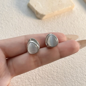 Detailed view of silver teardrop earrings featuring translucent white cat eye stones