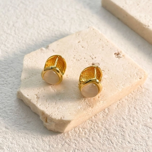 Macro detail of gold earrings featuring honeycomb texture and opal stone on stone base