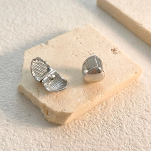 Macro shot of silver drop hoop earrings featuring polished finish and honeycomb texture details
