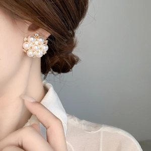 Close-up of pearl flower earrings with cubic zirconia insets and gold base on a model