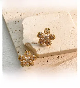Macro detail of 18K gold-plated snowflake earrings with white pearls and zircons