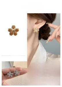 Close-up of 18K gold plated snowflake earrings with shiny zircons and pearls