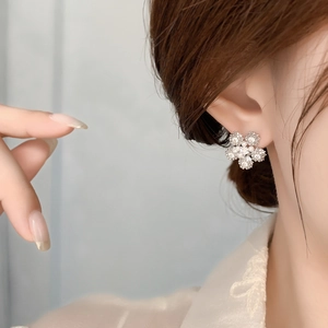 Elegant snowflake pearl earrings with 18K gold plating and zircon inlay on a model