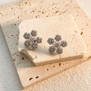 Close-up of snowflake stud earrings with 18k gold plating, cubic zirconia, and pearls
