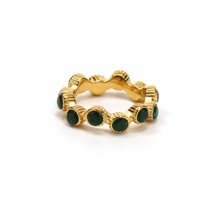 Anillo de titanio dorado con gemas verdes redondas y diseño de borde con textura