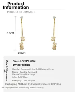 Détail des boucles d'oreilles à pompons en zircon plaqué or taille 6,6cm par 0,8cm sur blanc