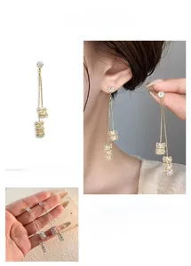 Détail de boucles d'oreilles pampilles de luxe avec cubes de cristal et finition dorée