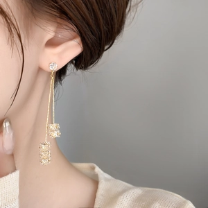 Gros plan de boucles d'oreilles pendantes dorées avec cristaux sur un mannequin femme