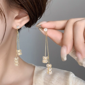 Élégantes boucles d'oreilles longues à franges dorées avec zircons sur un mannequin