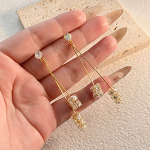 Boucles d'oreilles pendantes dorées avec des cristaux de zircone sur socle en pierre