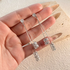 Détails de boucles d'oreilles pendantes argentées avec grappes de cristaux scintillants